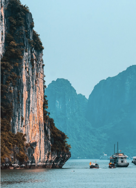 Scenic view of boats in Halong Bay, Vietnam, surrounded by majestic cliffs and tranquil waters.